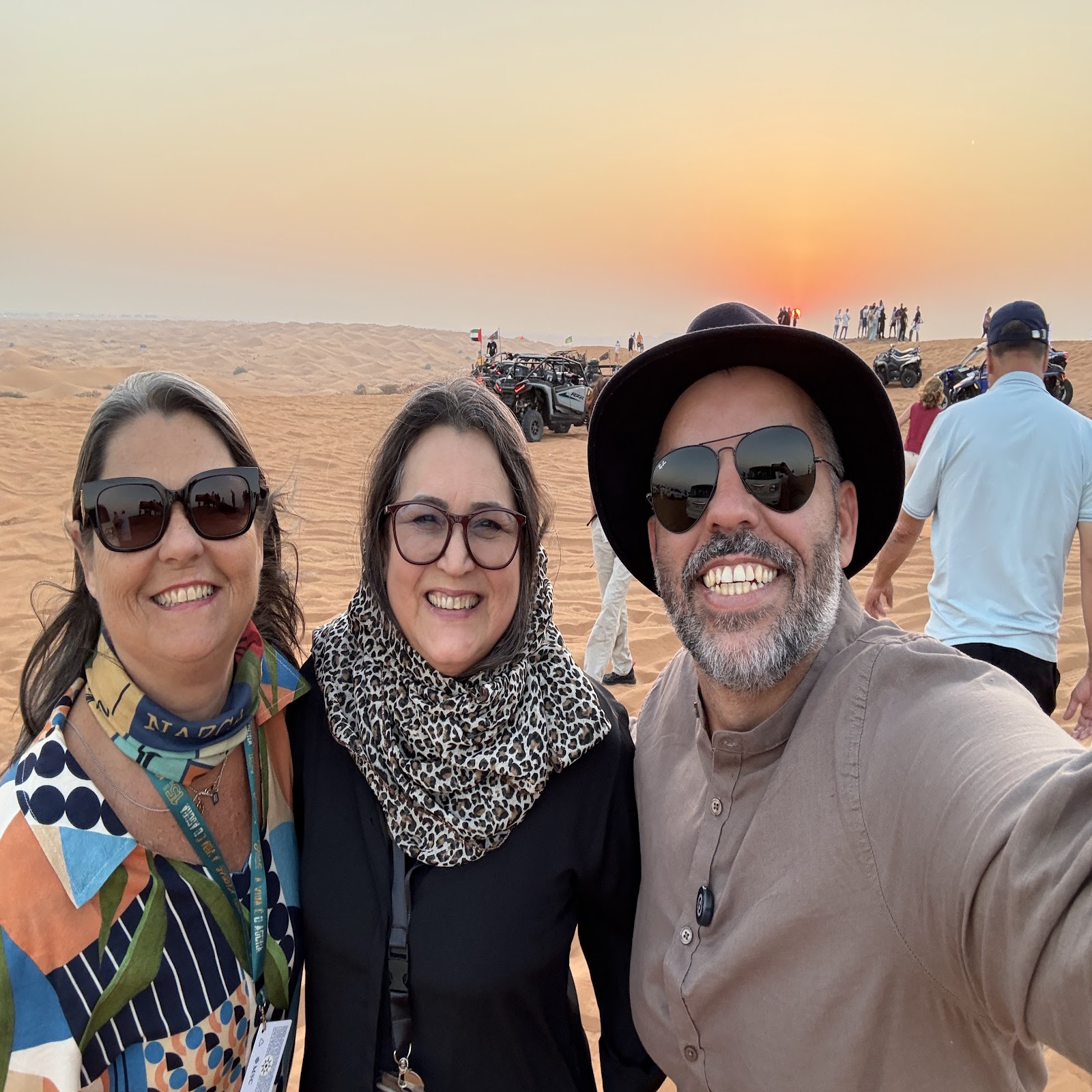 Viajantes no passeio pelo deserto de Dubai com buggies ao fundo