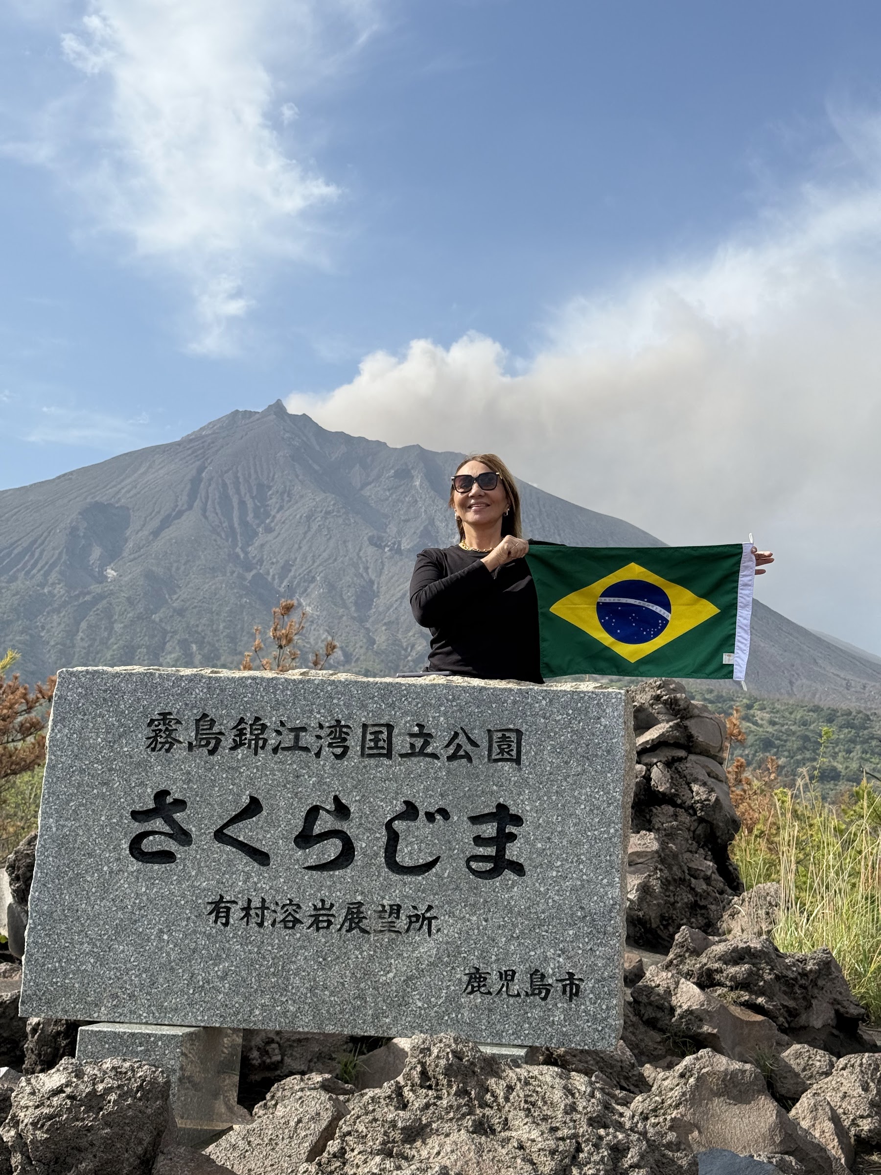 Viajante com bandeira do Brasil diante do vulcão em Kagoshima no Japão