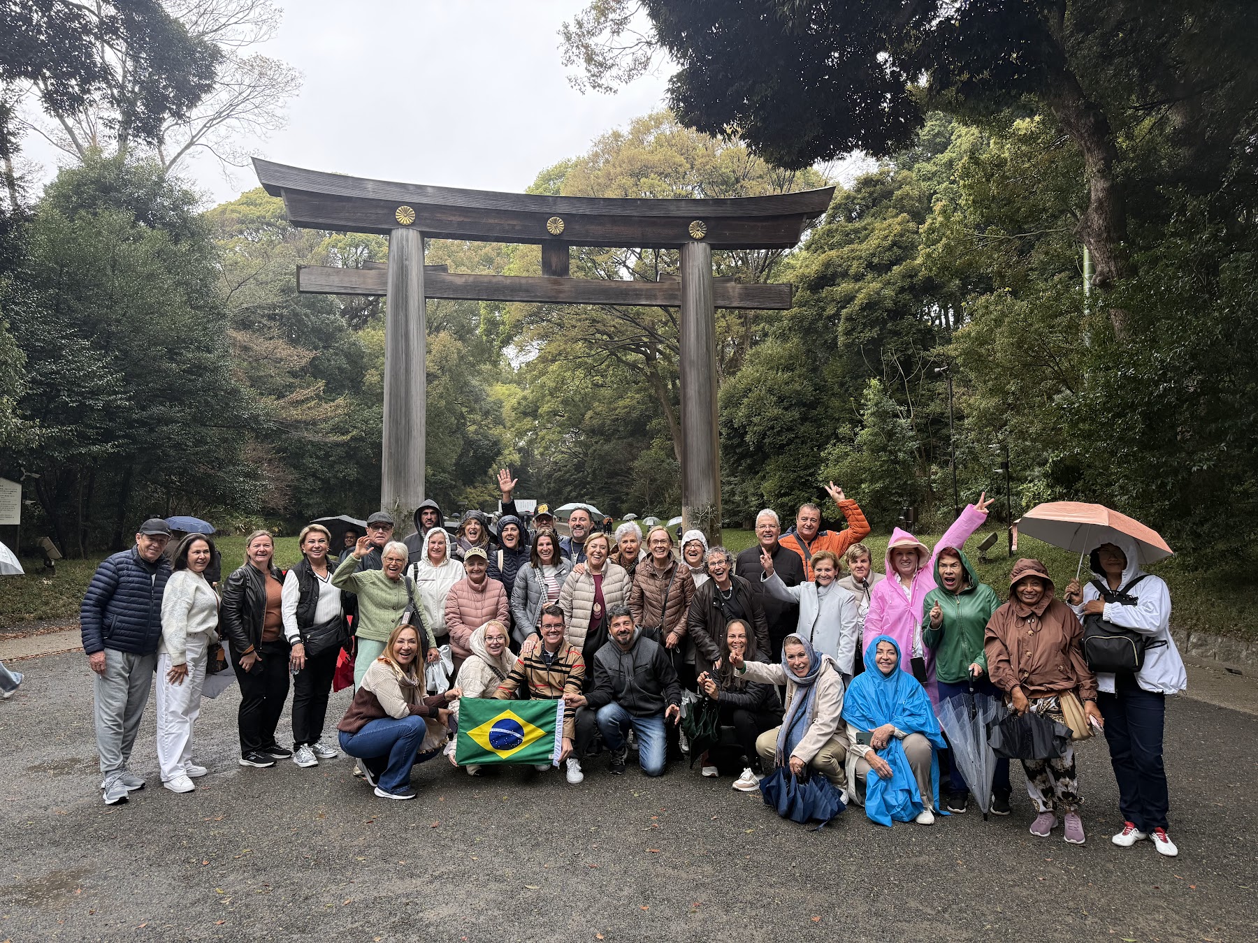 Grupo da Rigue reunido em frente a um torii no Japão em dia de chuva