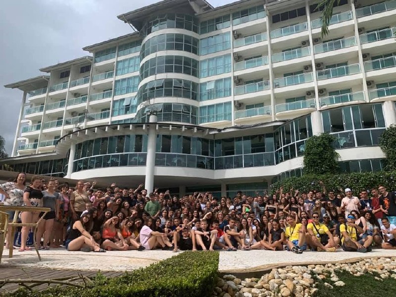 Grupo de viajantes da Rigue reunido em frente a hotel, representando a história construída antes dos reconhecimentos.