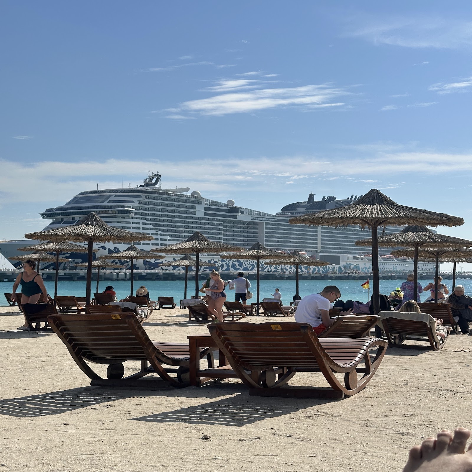 Praia de Sir Bani Yas com espreguiçadeiras, mar e navio ao fundo